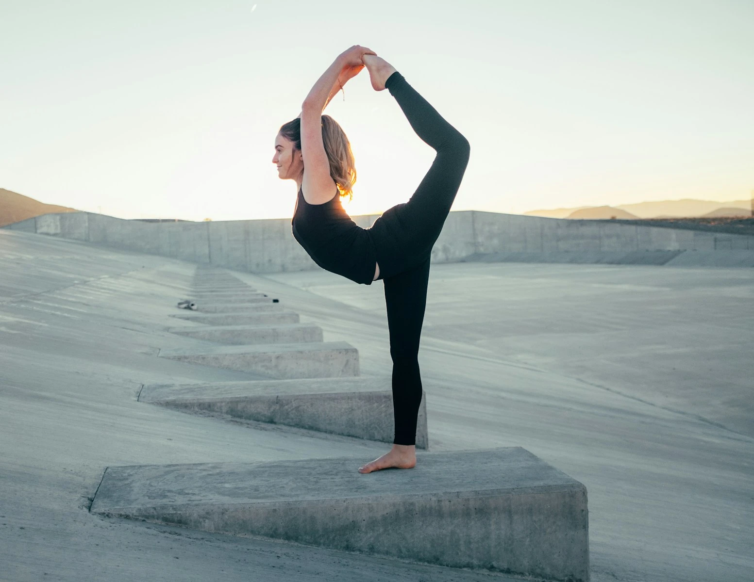 Yoga practitioner meditating at sunrise over a mountain lake