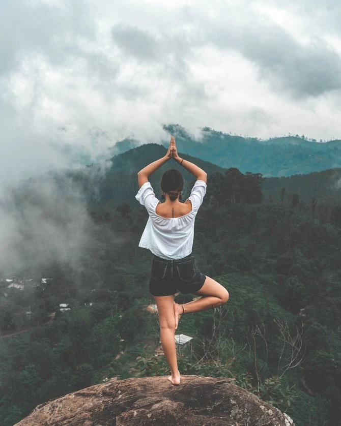 A practitioner in tree pose on a misty hillside