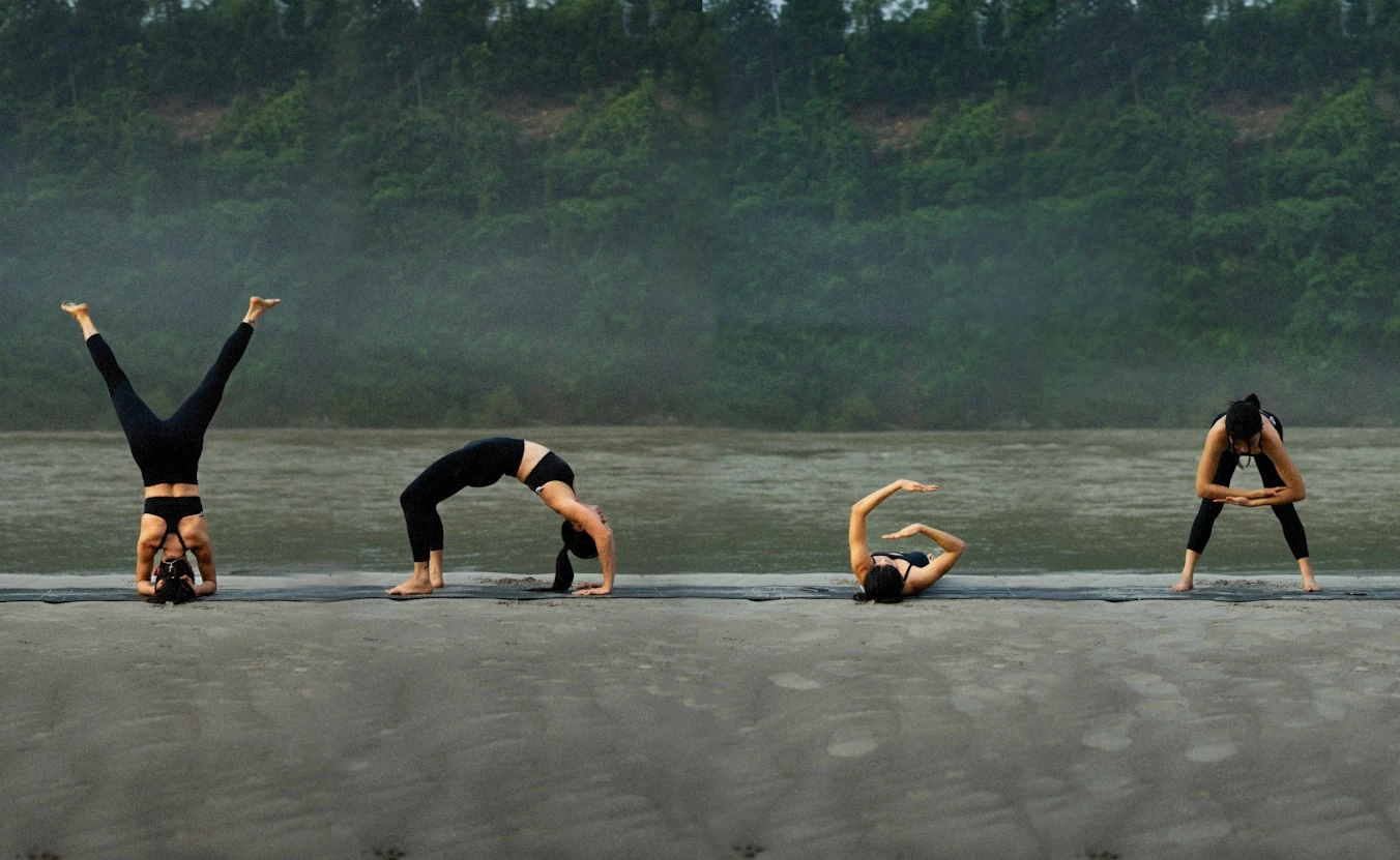 Four practitioners holding backbends and inversions on a lakeside shore